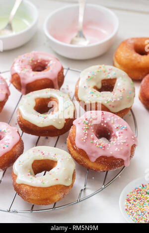 Beignets faits maison décoré de glaçage coloré et sucre coloré sur un fond clair. Banque D'Images