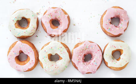 Beignets faits maison décoré de glaçage coloré et sucre coloré sur un fond clair. Banque D'Images