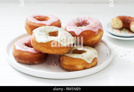 Beignets faits maison décoré de glaçage coloré et sucre coloré sur un fond clair. Banque D'Images