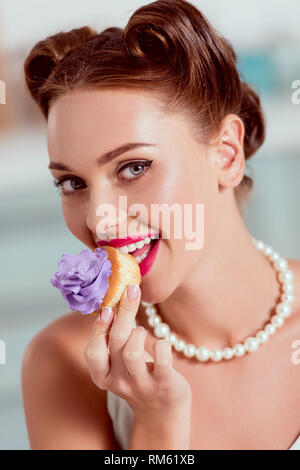 Belle pin up girl in pearl collier cupcake fait maison avec dégustation de crème de violette Banque D'Images