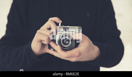 Un portrait d'un homme photographe portant l'objectif tout en maintenant un style rétro ou old fashioned caméra 35mm dans un style passe-temps libre Banque D'Images