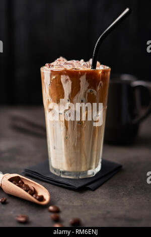Café crème avec de la glace dans un grand verre et les grains de café sur la table en béton foncé sur fond de bois noir. Boisson d'été froid. L'espace de copie pour le texte. Se Banque D'Images