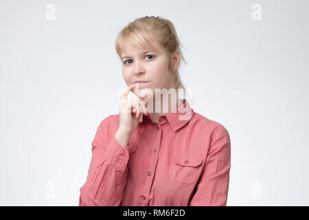 Penser blonde woman in pink shirt méditer sur quelque chose Banque D'Images