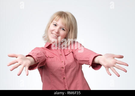 European woman in pink shirt avec poignée de mains tendues. Elle veut embrasser son amis. Banque D'Images