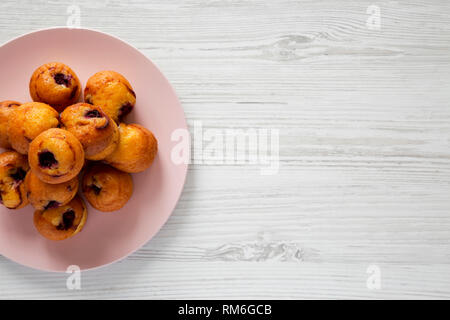 Vue de dessus, des mini-muffins avec cerise sur la plaque rose sur fond de bois blanc. Mise à plat, les frais généraux, d'en haut. Copier l'espace. Banque D'Images