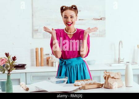 Pin up girl Smiling, debout près de la table de cuisine avec différents ingrédients Banque D'Images