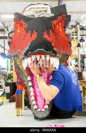 Briques lumineuses membre du personnel Ed Diment travaille sur une T-Rex fabriqué à partir de LEGO pendant une presse aperçu de zoo de Marwell de neuf à Brickosaurs Lego briques lumineuses dans l'AC BORDON, HAMPSHIRE. Banque D'Images