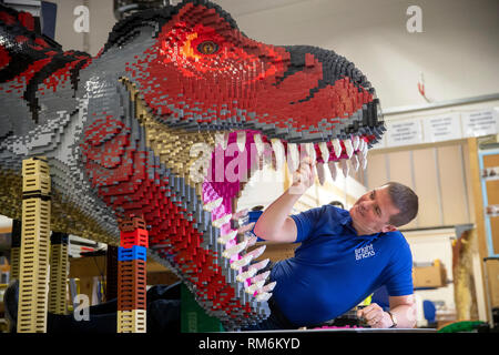 Briques lumineuses membre du personnel Ed Diment travaille sur une T-Rex fabriqué à partir de LEGO pendant une presse aperçu de zoo de Marwell de neuf à Brickosaurs Lego briques lumineuses dans l'AC BORDON, HAMPSHIRE. Banque D'Images