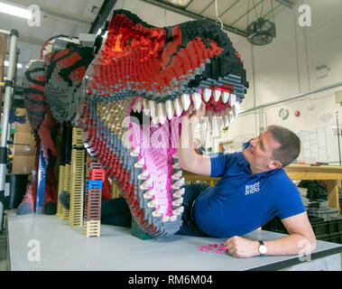 Briques lumineuses membre du personnel Ed Diment travaille sur une T-Rex fabriqué à partir de LEGO pendant une presse aperçu de zoo de Marwell de neuf à Brickosaurs Lego briques lumineuses dans l'AC BORDON, HAMPSHIRE. Banque D'Images