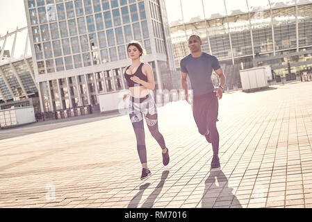 Vivre en bonne santé. Portrait of cute couple sportif fonctionnant ensemble dans la ville sous le soleil de la journée d'été. L'entraînement en milieu urbain. Couple en bonne santé. Motivation sport concept. Concept de remise en forme. La beauté des femmes. La vie en bonne santé. Ensemble de l'exercice Banque D'Images