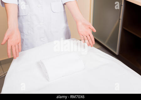 Portrait de pointage et permanent cosmetologist avec les mains à la table de massage au salon de beauté Banque D'Images