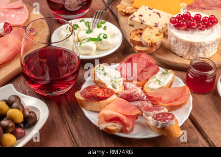 Dégustation de vin et le couplage. Wineglasses avec des sandwichs au fromage et une assiette de fromage sur un fond de bois foncé Banque D'Images