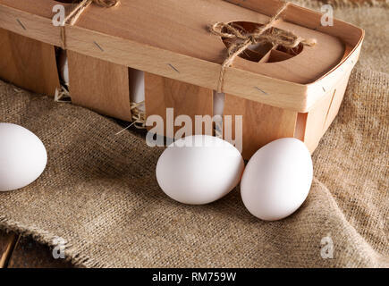 Close-up white oeufs dans un emballage en bois fort et sur de la toile de jute. L'emballage est constitué de bandes minces de placage en bois. Banque D'Images