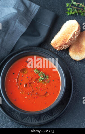 Bol de soupe aux tomates épicées garnies d'éclaboussure d'huile d'olive et poivre noir Banque D'Images