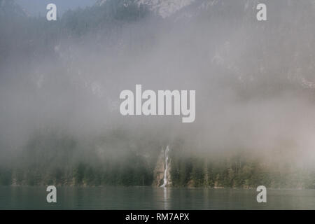 Vues de l'aménagement forestier parmi le brouillard en bordure du lac avec une cascade Banque D'Images