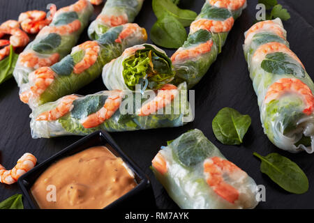 Rouleaux de printemps, rouleaux de papier de riz vietnamiens de laitue, de fèves germées, nouilles vermicelles, la menthe et les crevettes avec sauce aux arachides sur une ardoise noire tr Banque D'Images