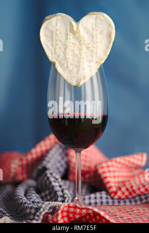 La composition avec Neufchatel, fromage normand (A.O.P.) et d'un verre de vin, sur un fond bleu. Banque D'Images