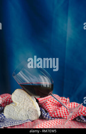 La composition avec Neufchatel, fromage normand (A.O.P.) et d'un verre de vin, sur un fond bleu. Banque D'Images