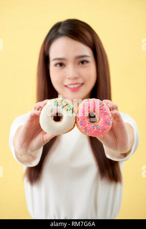 Belle jeune femme asiatique portaient des t-shirt blanc, sourire et bonne humeur, eating, isolé sur fond jaune Banque D'Images