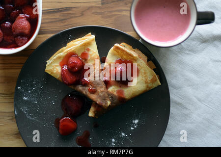 Crêpes maison avec du fromage cottage et les fraises dans une assiette. Fond de bois. Banque D'Images
