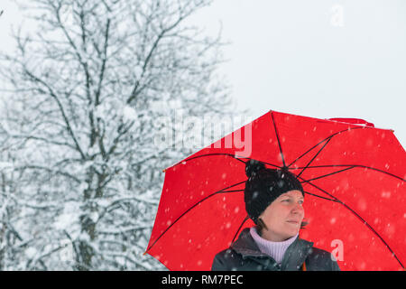Triste déçu dans femme debout en hiver neige sous grand parapluie rouge Banque D'Images