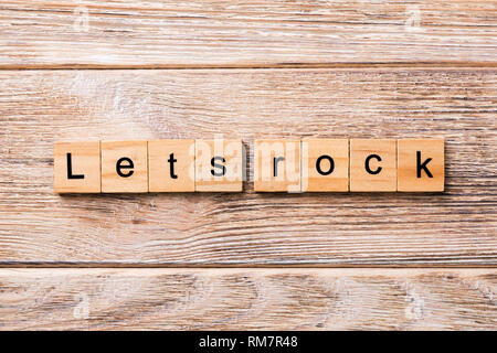 Let's Rock mot écrit sur une cale en bois. Lets Rock texte sur table en bois pour votre conception, concept. Banque D'Images