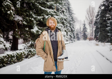 Thème Sports d'hiver. Portrait. Beau jeune homme de race blanche avec de longs cheveux et barbe rouge. En hiver pose modèle snow park contre l'arrière-plan de la fo Banque D'Images