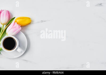 Tasse de café avec des tulipes sur la table de marbre blanc. Les fleurs du printemps. Vue d'en haut. L'espace de copie pour le texte. Concept de printemps. Banque D'Images