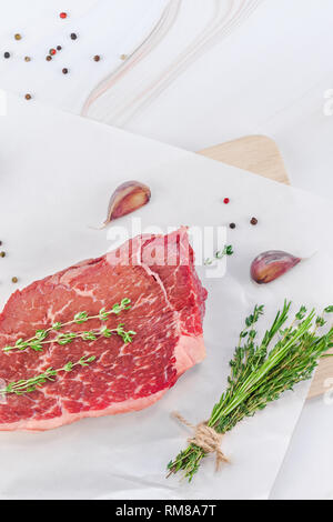 Creative haut voir télévision laïcs de la viande de boeuf cru frais faux filet de boeuf au poivre et à l'ail romarin thym herbes champignons sur fond de table en marbre blanc w Banque D'Images