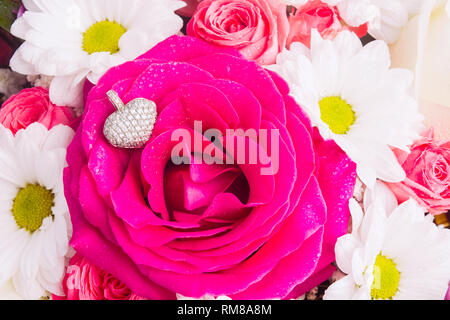 Pendentif en or blanc en forme de coeur avec plus de rose rose comme cadeau d'amour pour la Saint Valentin ou anniversaire. Beau bouquet couleur délicate avec juif Banque D'Images