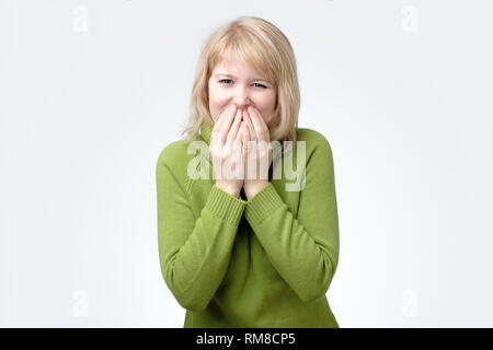 Bonne recherche jeune femme giggles joyeusement, se couvrir la bouche comme essaie arrêter de rire Banque D'Images