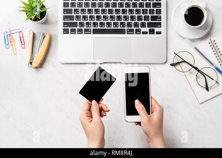 Une femme est en train de faire un achat en ligne, des maquettes et de carte de crédit sur téléphone cellulaire mobile office bureau isolé sur fond en mode copie, spac Banque D'Images