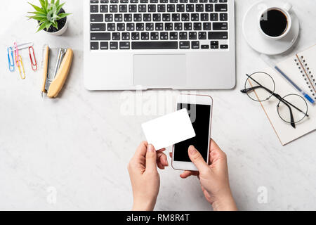 Une femme est en train de faire un achat en ligne, des maquettes et de carte de crédit sur téléphone cellulaire mobile office bureau isolé sur fond en mode copie, spac Banque D'Images