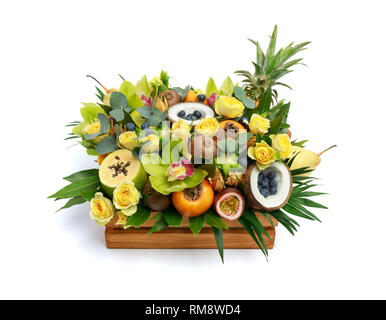 Boîte en bois avec plein de fruits exotiques et de fleurs isolé sur fond blanc Banque D'Images