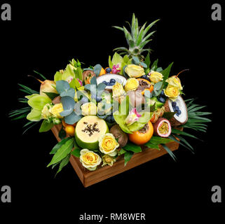 Boîte en bois avec plein de fruits exotiques et de fleurs isolé sur fond noir comme un cadeau Banque D'Images