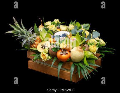 Boîte en bois avec plein de fruits exotiques et de fleurs isolé sur fond noir qu'un modèle de carte de souhaits Banque D'Images