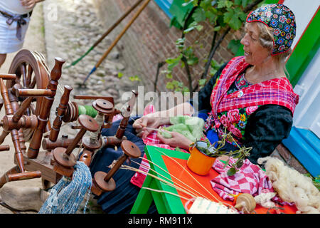 Femme en costume traditionnel néerlandais filage de la laine en face d'une authentique maison peinte Banque D'Images