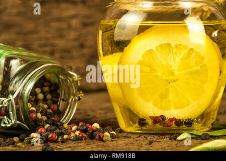 L'huile d'olive parfumée au citron et les grains de poivre dans le flacon en verre sur fond de bois vieux Banque D'Images