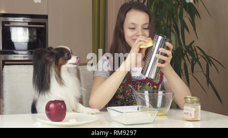 Teen girl with dog Papillon préparer des cookies, pétrir la pâte Banque D'Images