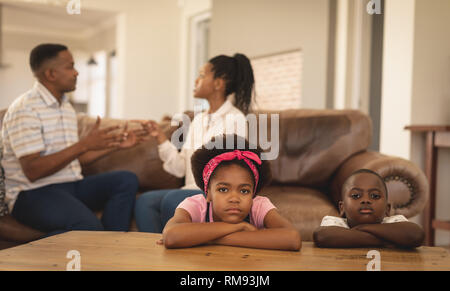 Les enfants afro-américains s'appuyant sur table tout en soutenant les parents sur le canapé Banque D'Images
