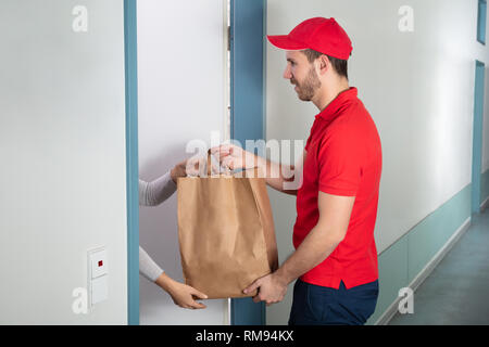 Un jeune homme beau sac de papier donnant à la femme à la maison Banque D'Images