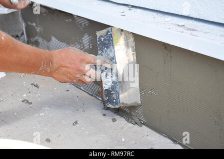 Constructeur maison plâtrage des murs de fondation à l'aide d'une spatule Banque D'Images