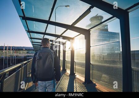 Jeune homme avec balades à dos d'aérogare au coucher du soleil. Banque D'Images