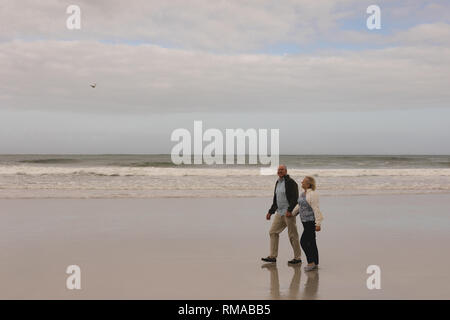 Senior couple marche main dans la main à la plage Banque D'Images