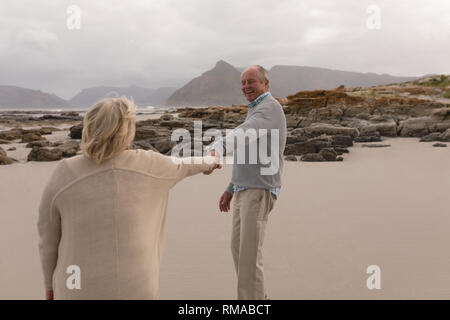 Happy senior man holding hand of senior woman at the beach Banque D'Images