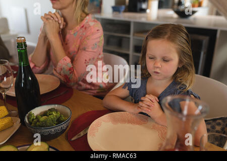 Mère et fille priant ensemble avant having meal Banque D'Images