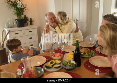 Famille en interaction les uns avec les autres tout en ayant des repas sur table à manger Banque D'Images