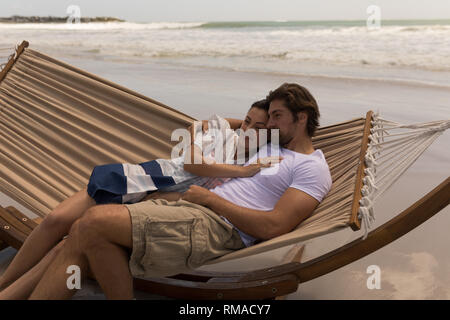 Young couple relaxing on hammock at beach Banque D'Images