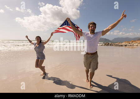 Happy young couple with arms outstretched holding american flag Banque D'Images