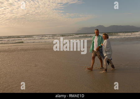 Senior couple marche main dans la main sur la plage Banque D'Images